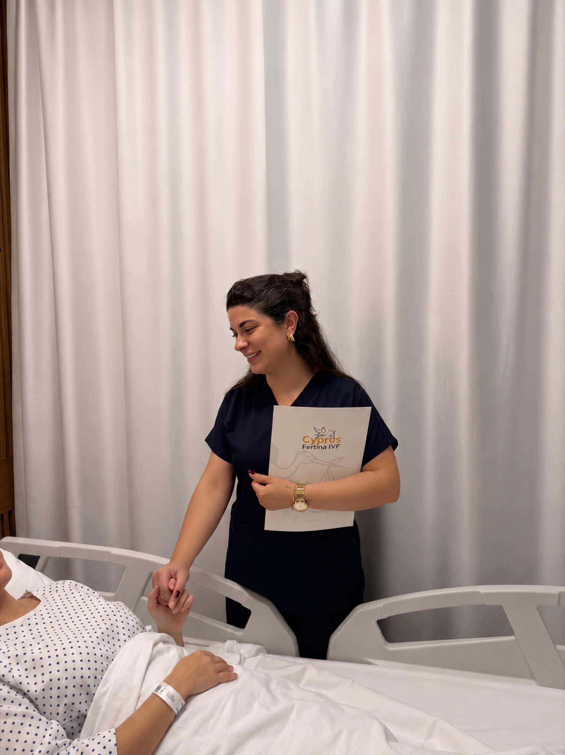 Fertina nurse holding a patient's hand at the bedside